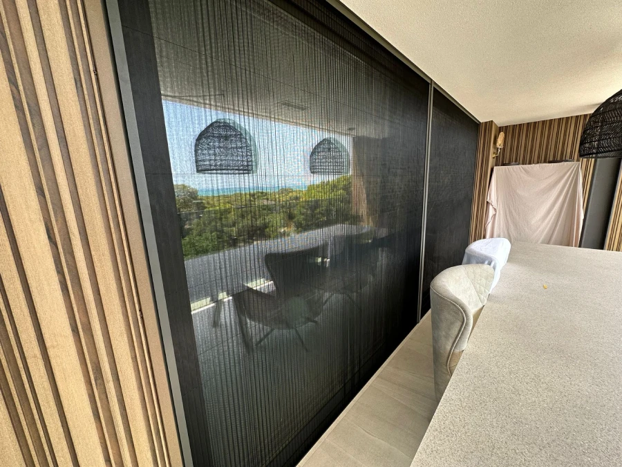 Ventanal corredero de un dormitorio con mosquitera y vistas al mar