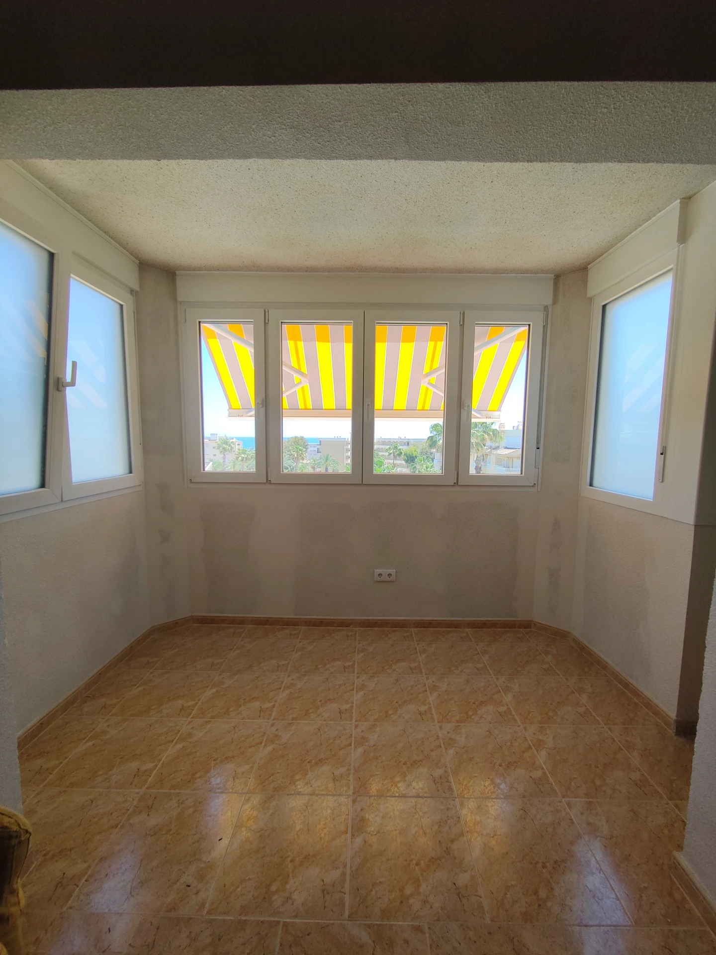 Balcon convertido en galeria con ventanas de aluminio y toldo exterior