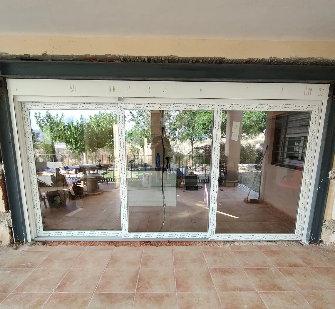 Porche cerrado con puertas correderas de PVC blanco que dan a una terraza