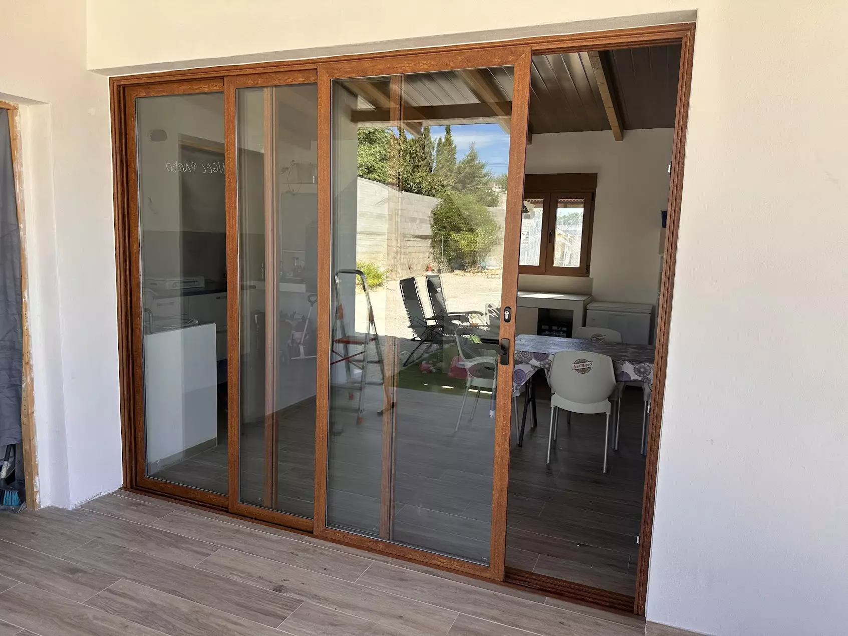 Puerta corredera de aluminio de tres hojas con acabado madera que comunica con un porche