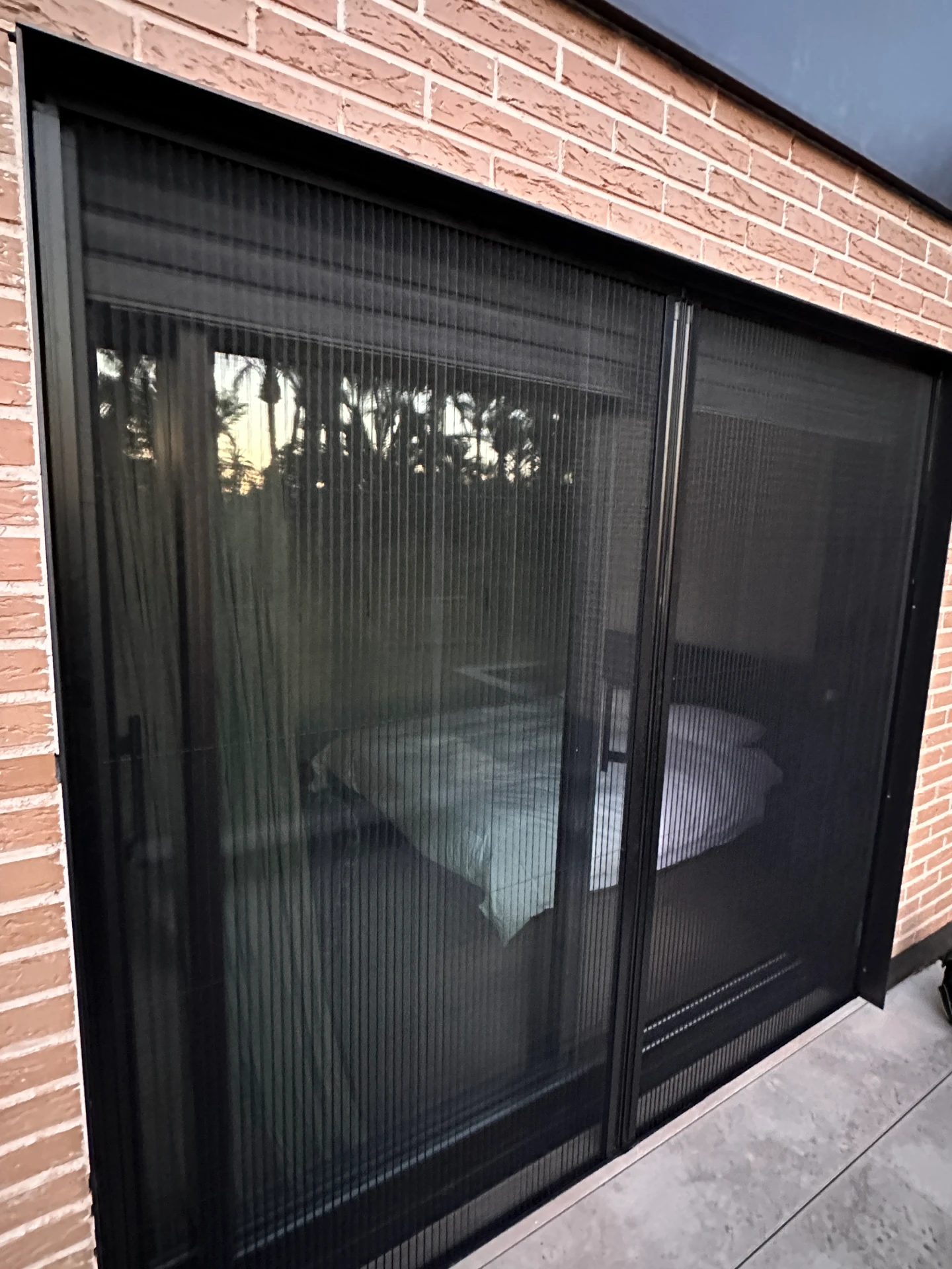 Mosquitera plisada negra montada en la puerta corredera de un dormitorio en Elche