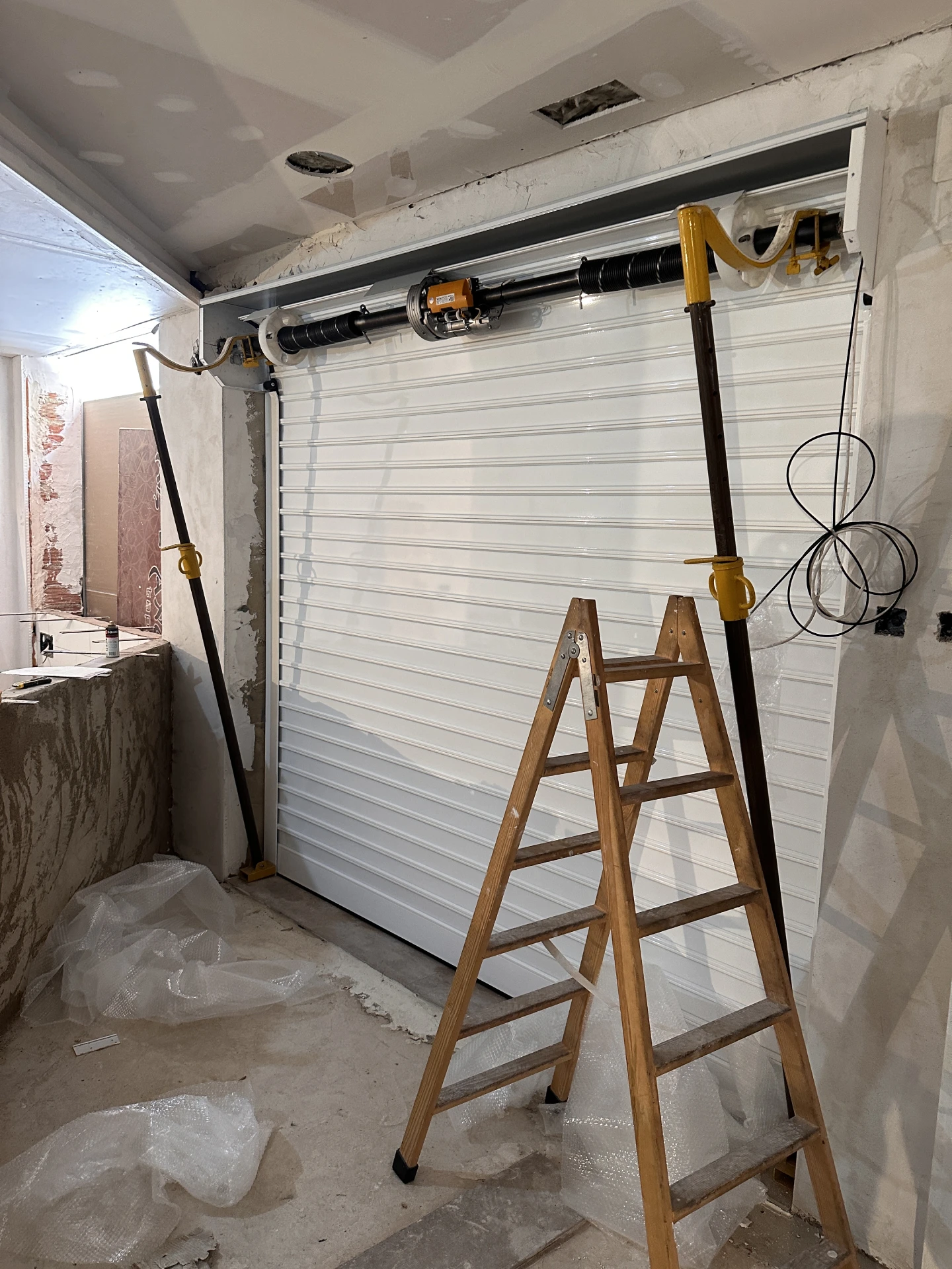Instalación de una persiana blanca con su cajón durante la obra