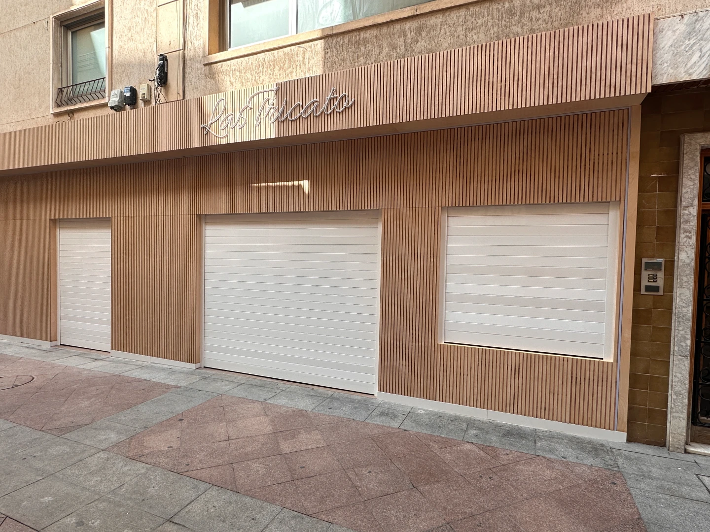 Ventanas con persianas blancas en una fachada con revestimiento de listones de madera