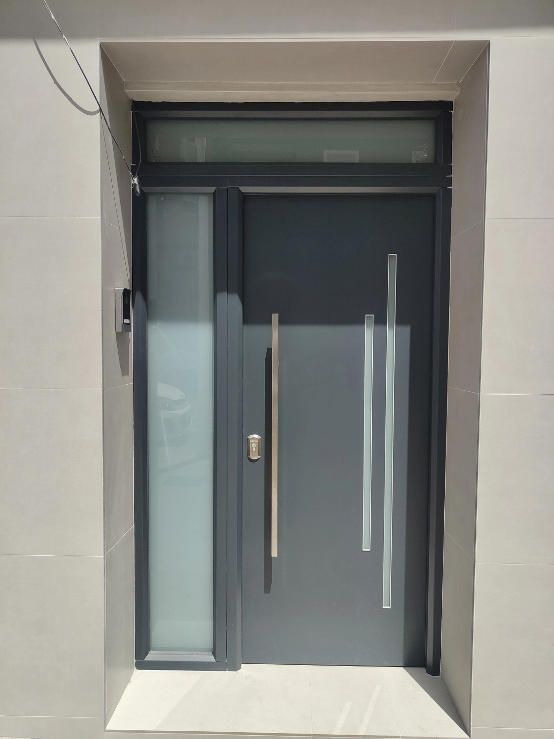 Puerta de entrada acristalada de aluminio gris antracita con tirador vertical