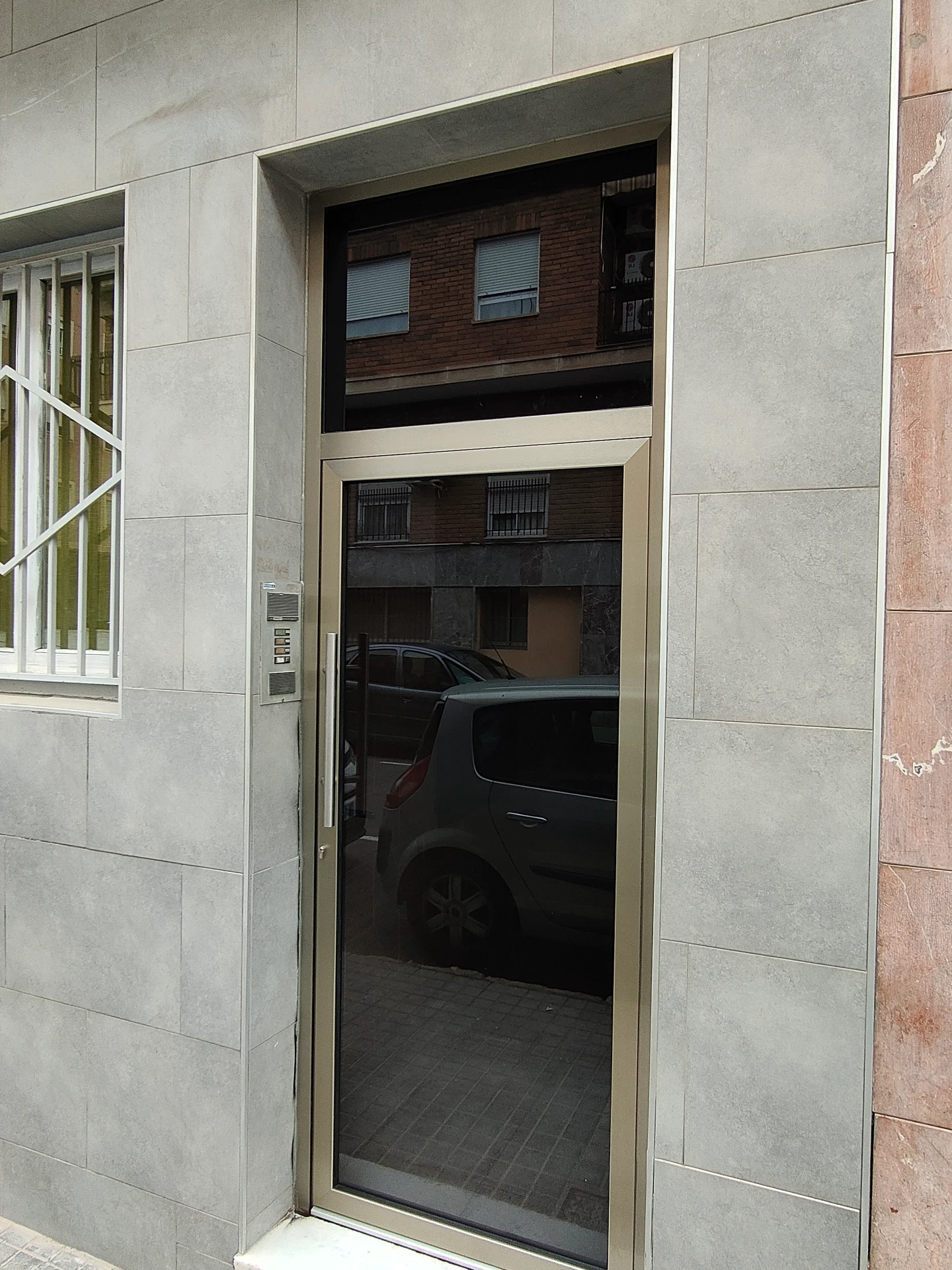 Puerta de entrada de aluminio con vidrio en el acceso a un edificio de viviendas