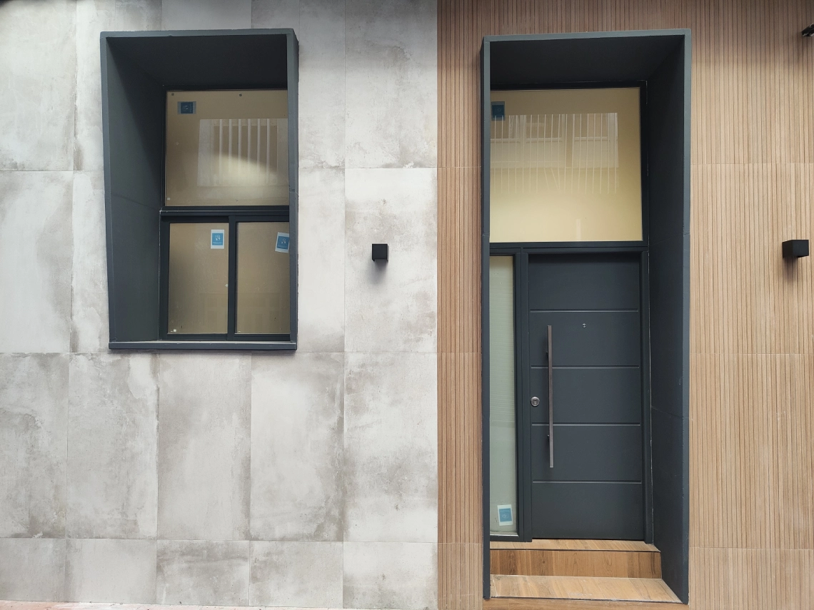 Puerta y ventana de aluminio gris antracita en una fachada con revestimiento de madera