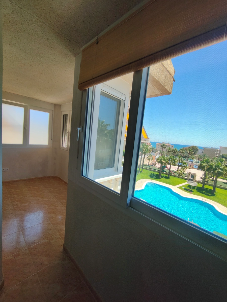 Ventana corredera de PVC blanco en una galeria con vistas a la piscina y al mar