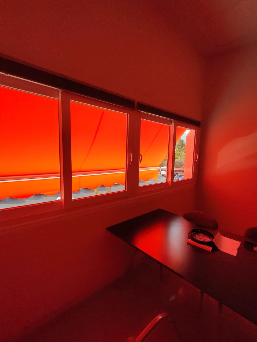 Ventanas de PVC blancas con un toldo naranja desplegado en el exterior