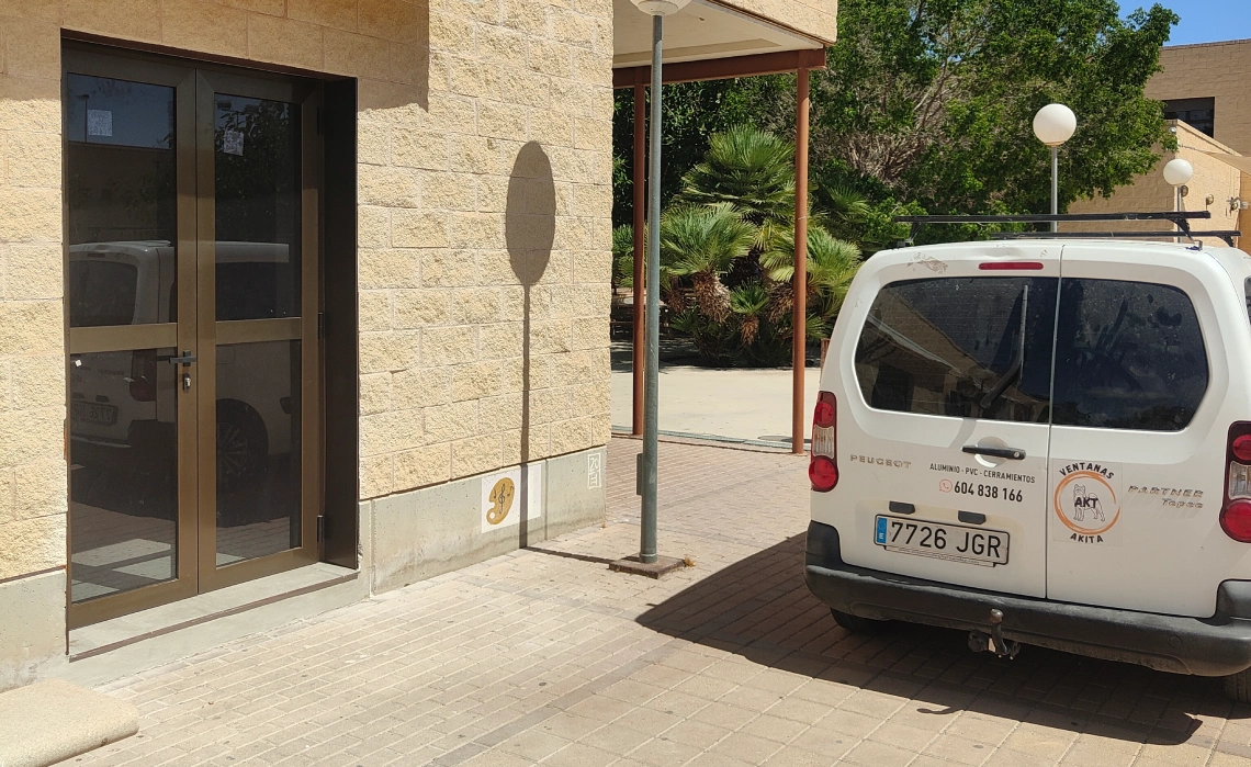 Fachada del local de Ventanas Akita con puerta de aluminio y furgoneta aparcada delante