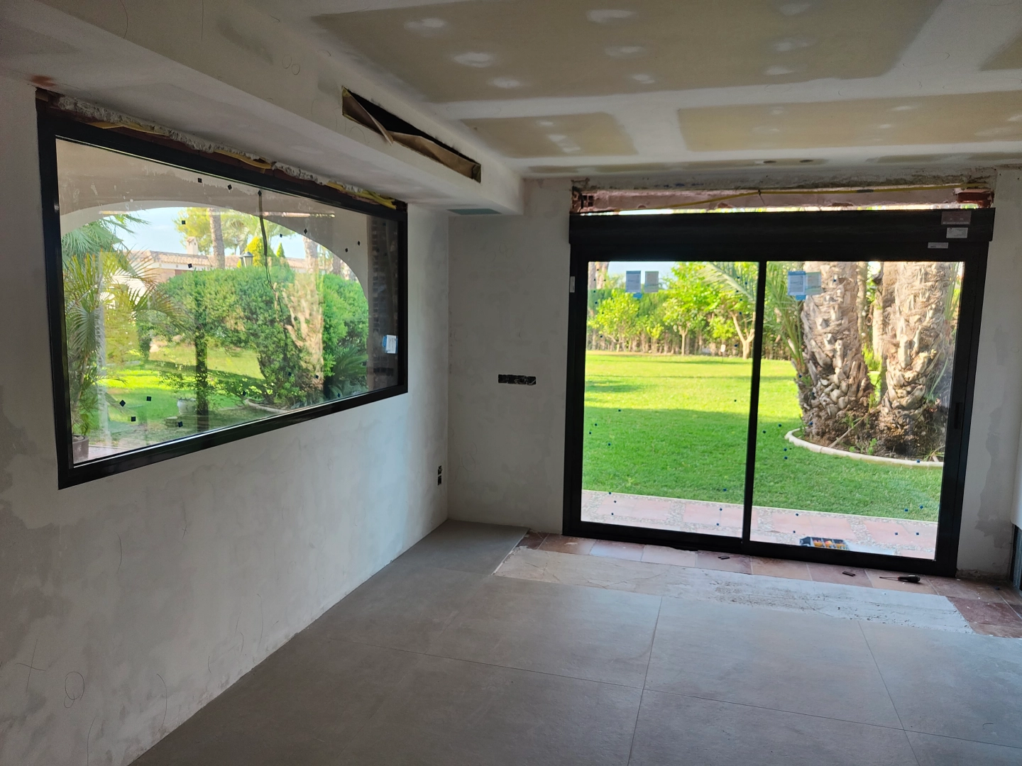 Ventanal fijo panoramico y puerta corredera de aluminio negro recien instalados en una reforma