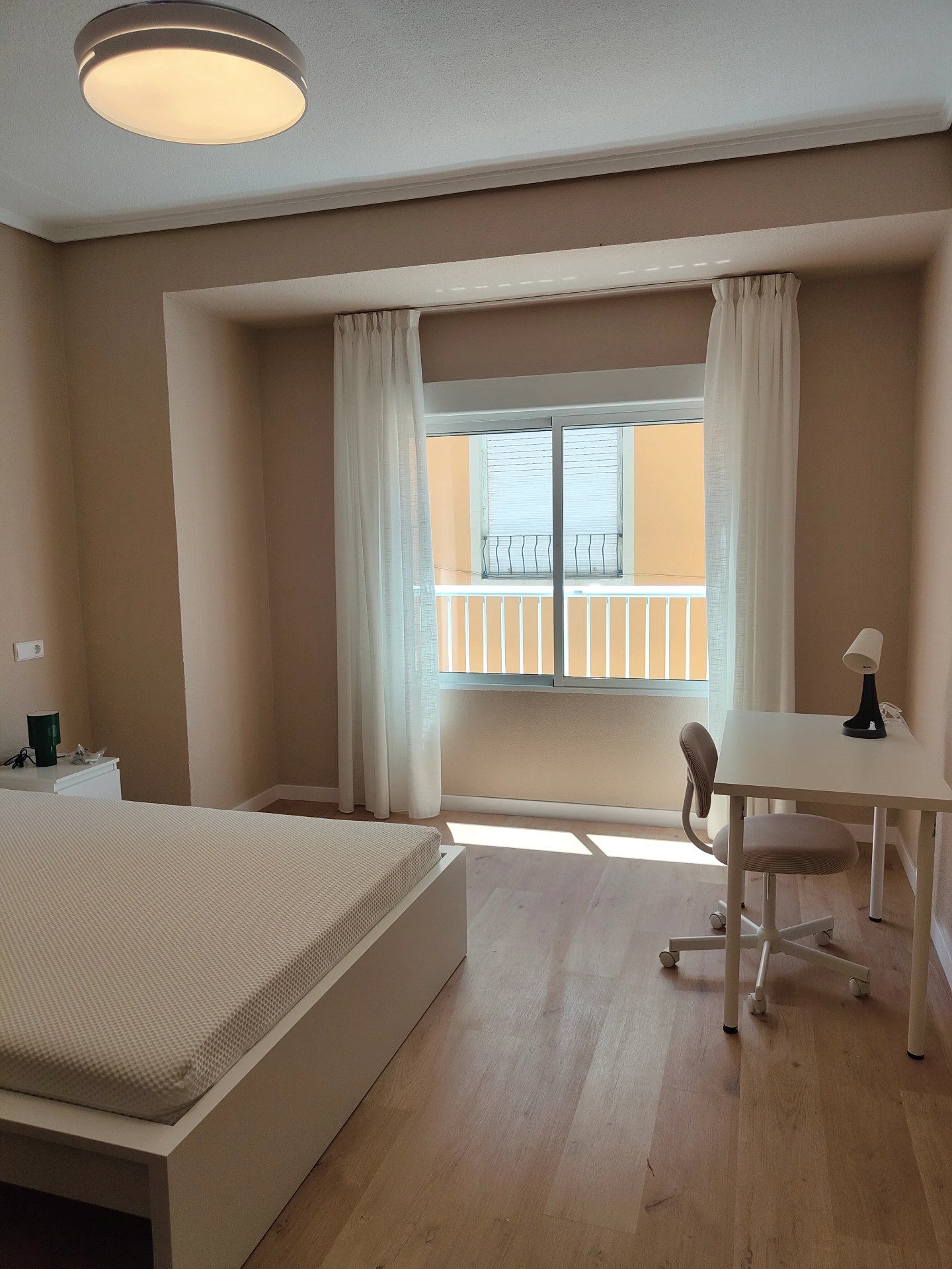 Dormitorio con balconera de aluminio y cortinas que da a un balcon